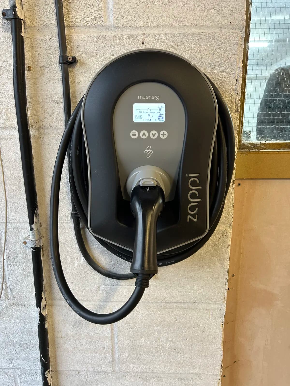 myenergi Zappi home EV charger on a block wall