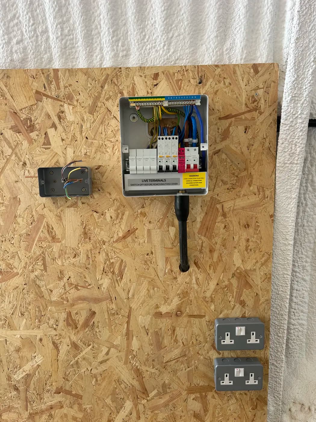 Double sockets beside a small consumer unit on an OSB board